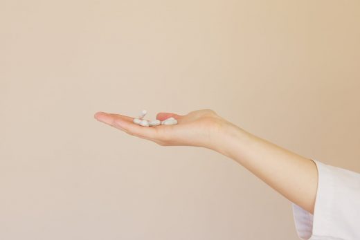 crop female pharmacist with pile of white pills on palm