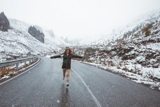 woman running on road in snowy mountains